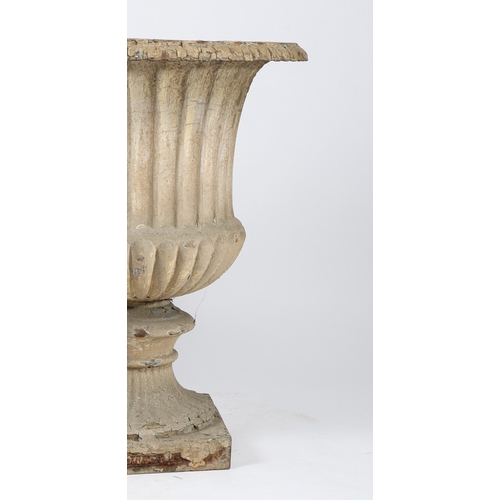 85 - A PAIR OF CAST IRON GARDEN URNS. of classical form with reeded bodies and stems, raised on square pl... 