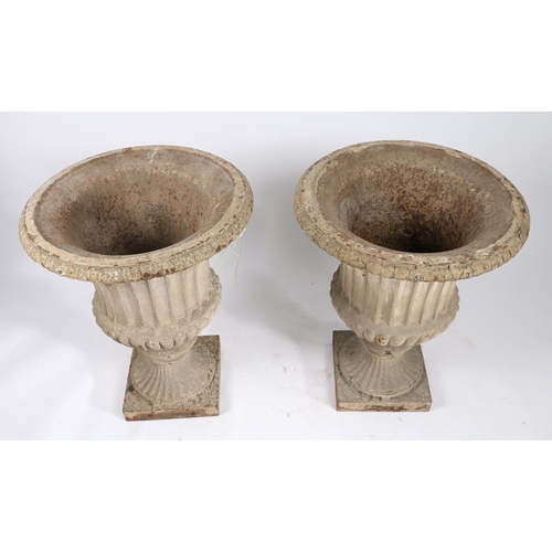 85 - A PAIR OF CAST IRON GARDEN URNS. of classical form with reeded bodies and stems, raised on square pl... 