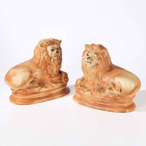 90 - A PAIR OF VICTORIAN STAFFORDSHIRE LIONS. modelled in recumbent positions with gilt highlighted manes... 