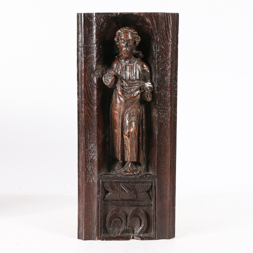 516 - A 16TH CENTURY OAK AND POLYCHROME CARVING. Designed as a male Saint, standing within an arched niche... 