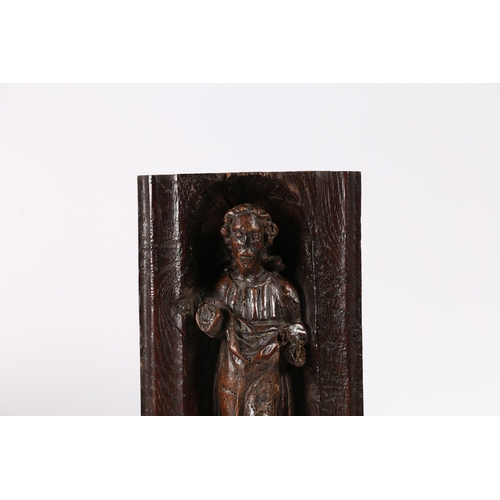 516 - A 16TH CENTURY OAK AND POLYCHROME CARVING. Designed as a male Saint, standing within an arched niche... 