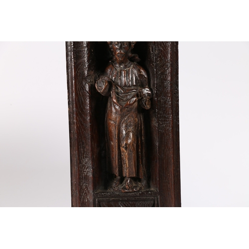 516 - A 16TH CENTURY OAK AND POLYCHROME CARVING. Designed as a male Saint, standing within an arched niche... 