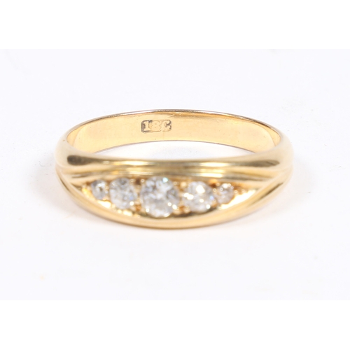 11 - AN 18 CARAT GOLD AND DIAMOND RING. the oval reeded head set with five graduated diamonds, ring size ... 