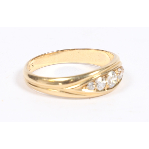 11 - AN 18 CARAT GOLD AND DIAMOND RING. the oval reeded head set with five graduated diamonds, ring size ... 