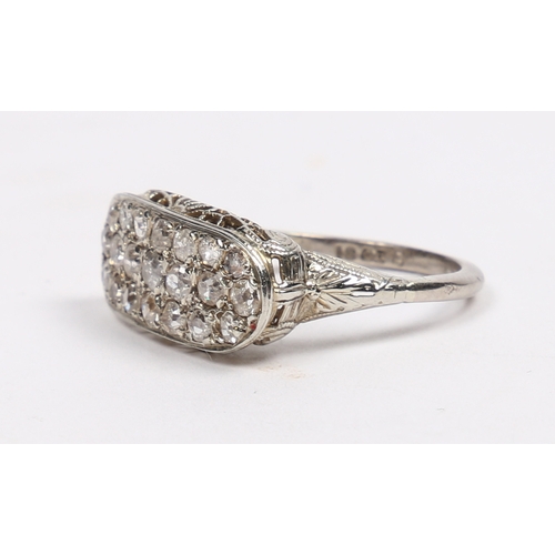 20 - AN 18 CARAT WHITE GOLD AND DIAMOND RING. the oval head set with 21 round cut diamonds and with pierc... 