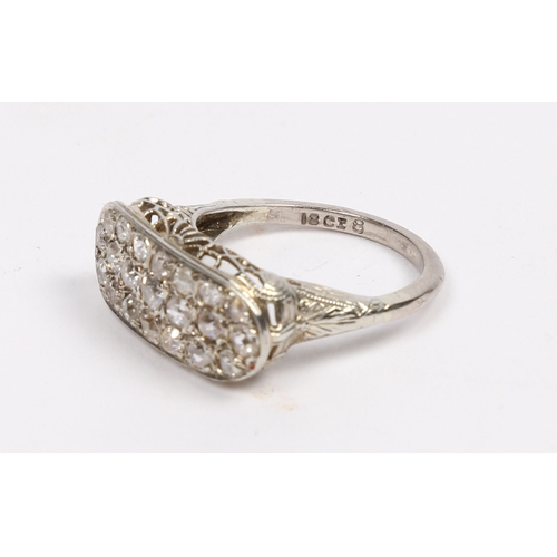 20 - AN 18 CARAT WHITE GOLD AND DIAMOND RING. the oval head set with 21 round cut diamonds and with pierc... 