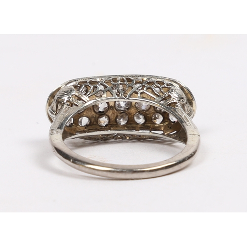 20 - AN 18 CARAT WHITE GOLD AND DIAMOND RING. the oval head set with 21 round cut diamonds and with pierc... 