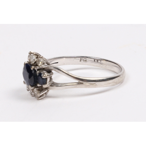 32 - AN 18 CARAT WHITE GOLD SAPPHIRE AND DIAMOND RING. the central oval facet cut sapphire flanked by two... 