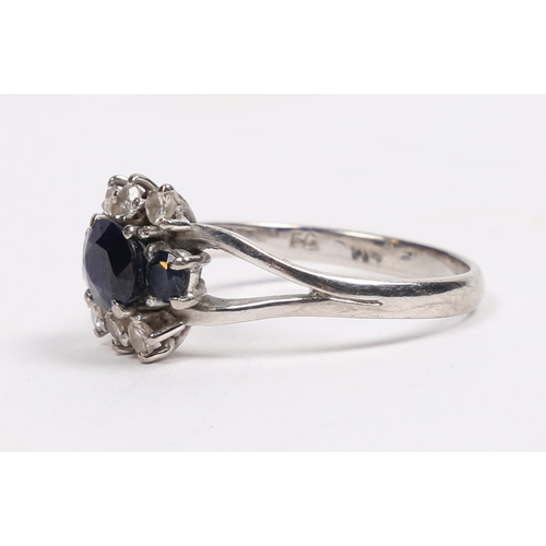 32 - AN 18 CARAT WHITE GOLD SAPPHIRE AND DIAMOND RING. the central oval facet cut sapphire flanked by two... 