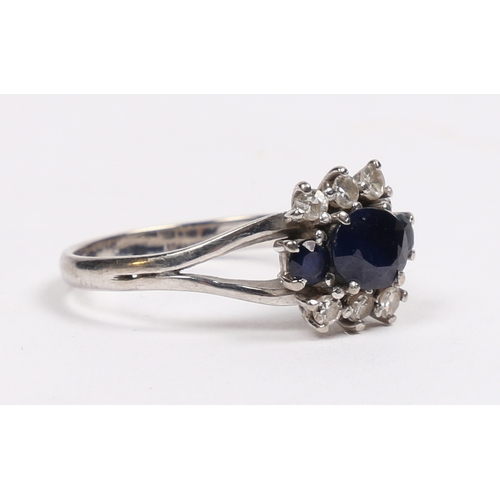 32 - AN 18 CARAT WHITE GOLD SAPPHIRE AND DIAMOND RING. the central oval facet cut sapphire flanked by two... 