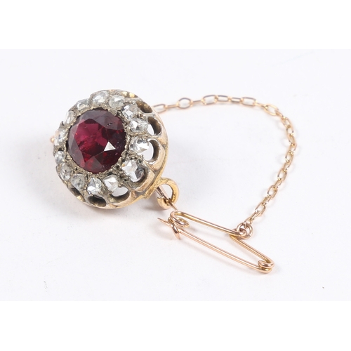 38 - AN EDWARDIAN GARNET AND DIAMOND BROOCH. the central oval facet cut garnet surrounded by a band of ro... 