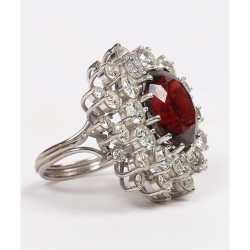 39 - A SUBSTANTIAL DIAMOND AND GARNET CLUSTER RING. the central oval face cut garnet surrounded by round ... 