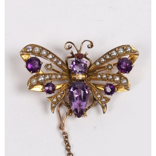 40 - A 9 CARAT GOLD, AMETHYST AND SEED PEARL BUTTERFLY BROOCH. modelled with wings spread, with garnet se... 