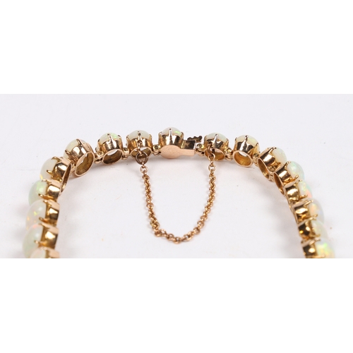 45 - A YELLOW METAL AND OPAL BRACELET. set with twenty-six graduated oval opals, the clasp with security ... 