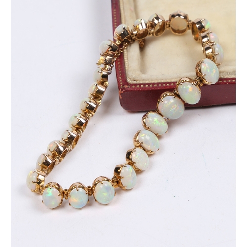 45 - A YELLOW METAL AND OPAL BRACELET. set with twenty-six graduated oval opals, the clasp with security ... 