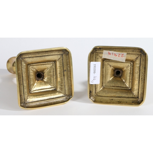 51 - A PAIR OF GEORGE II BRASS SQUARE-BASE CANDLESTICKS, CIRCA 1730. Each with slightly octagonal tulip-s... 