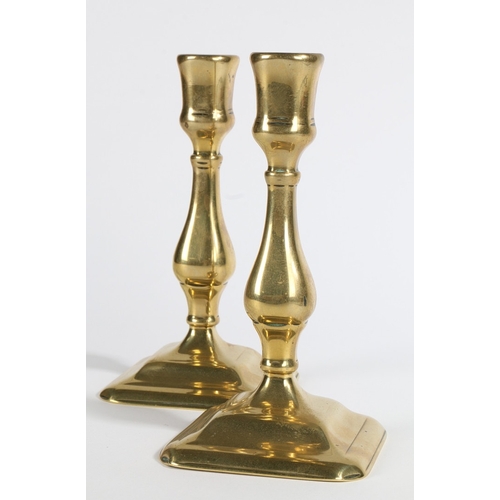 51 - A PAIR OF GEORGE II BRASS SQUARE-BASE CANDLESTICKS, CIRCA 1730. Each with slightly octagonal tulip-s... 