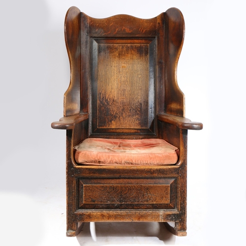 58 - A GEORGE II OAK LAMBING-TYPE WINGED AND ROCKING ARMCHAIR, CIRCA 1750. Having a fielded back panel, s... 