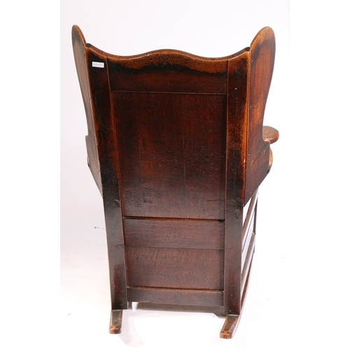 58 - A GEORGE II OAK LAMBING-TYPE WINGED AND ROCKING ARMCHAIR, CIRCA 1750. Having a fielded back panel, s... 