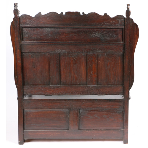 31 - A 19TH CENTURY OAK SETTLE IN THE 17TH CENTURY MANNER. having a scroll cresting rail with finials in ... 