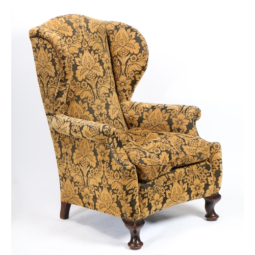 41 - A GEORGE III WINGBACK ARMCHAIR. upholstered in a golden floral fabric and having studded arms raised... 