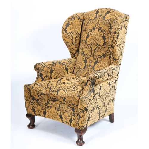 41 - A GEORGE III WINGBACK ARMCHAIR. upholstered in a golden floral fabric and having studded arms raised... 