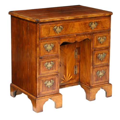 81 - A QUEEN ANNE WALNUT KNEEHOLE DESK. having a cross banded top with shaped corners above seven cross b... 