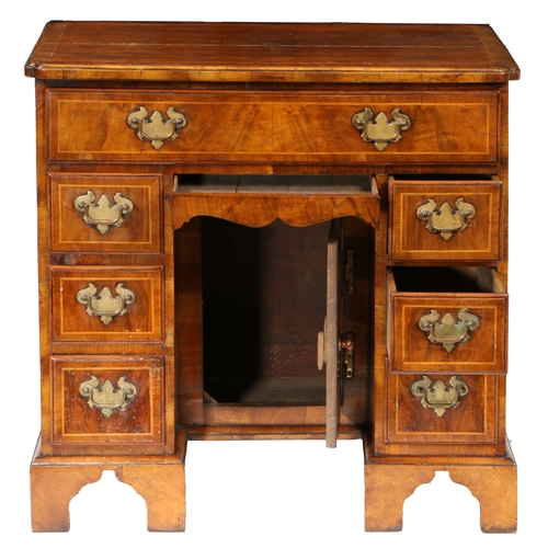 81 - A QUEEN ANNE WALNUT KNEEHOLE DESK. having a cross banded top with shaped corners above seven cross b... 