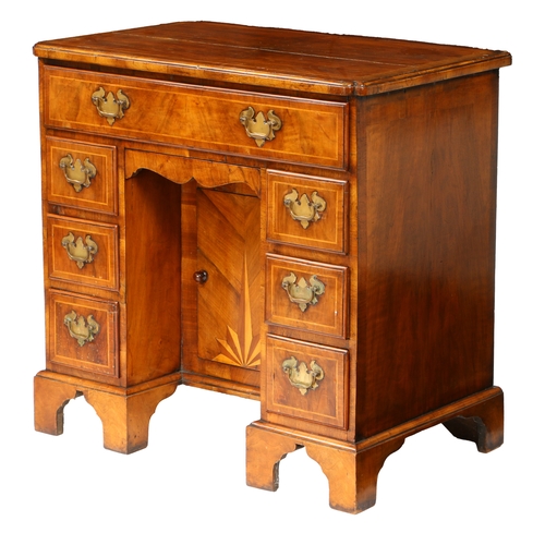 81 - A QUEEN ANNE WALNUT KNEEHOLE DESK. having a cross banded top with shaped corners above seven cross b... 