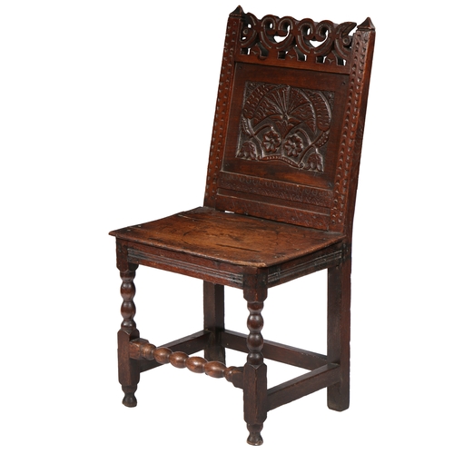 183 - AN UNCOMMON CHARLES II OAK BACKSTOOL, CHESHIRE, CIRCA 1680. The back panel carved with a large carna... 