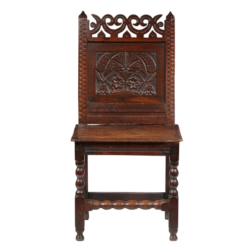 183 - AN UNCOMMON CHARLES II OAK BACKSTOOL, CHESHIRE, CIRCA 1680. The back panel carved with a large carna... 