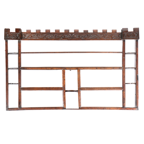 196 - AN OAK HANGING RACK, 18TH CENTURY TIMBERS. Having a castellated leaf-scroll carved frieze, three cen... 