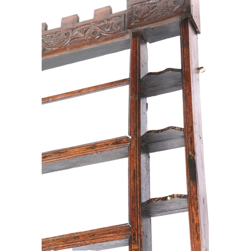 196 - AN OAK HANGING RACK, 18TH CENTURY TIMBERS. Having a castellated leaf-scroll carved frieze, three cen... 