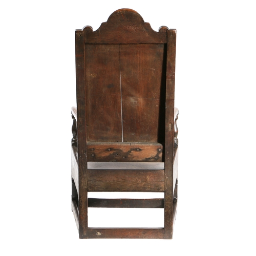 20 - A 17TH CENTURY OAK ARMCHAIR. The arched top rail above a fielded panel back and a solid seat flanked... 
