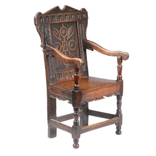 201 - A CHARLES I OAK PANEL-BACK OPEN ARMCHAIR, CIRCA 1640. Having a strap-work carved back panel, below a... 