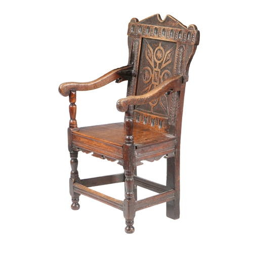 201 - A CHARLES I OAK PANEL-BACK OPEN ARMCHAIR, CIRCA 1640. Having a strap-work carved back panel, below a... 