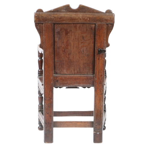 201 - A CHARLES I OAK PANEL-BACK OPEN ARMCHAIR, CIRCA 1640. Having a strap-work carved back panel, below a... 