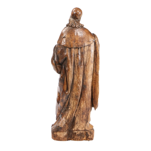 204 - A LARGE 17TH CENTURY WALNUT CARVED FIGURE. With long flowing hair below a skull cap, wearing a cape ... 