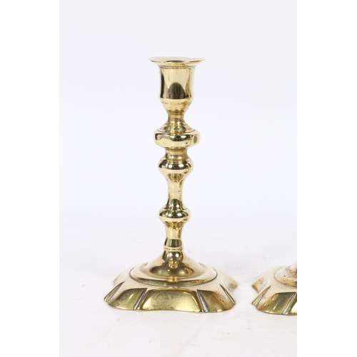 237 - A PAIR OF GEORGE II BRASS CANDLESTICKS. with a raised flange above a knopped stem on a petal base, 1... 