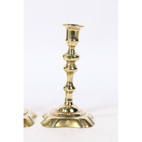 237 - A PAIR OF GEORGE II BRASS CANDLESTICKS. with a raised flange above a knopped stem on a petal base, 1... 