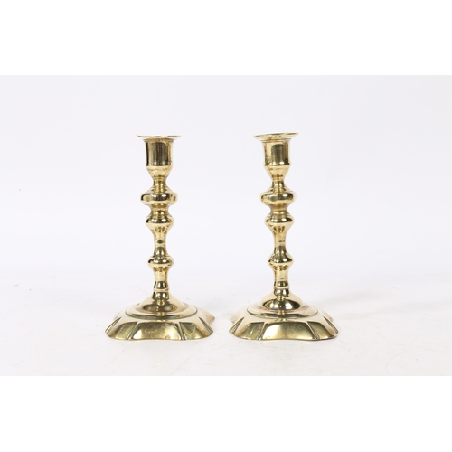 237 - A PAIR OF GEORGE II BRASS CANDLESTICKS. with a raised flange above a knopped stem on a petal base, 1... 