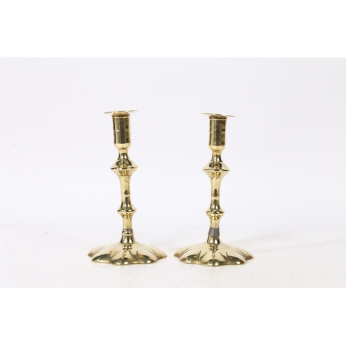 239 - A PAIR OF GEORGE II BRASS CANDLESTICKS. with a broad flange above a knopped stem set on a star petal... 