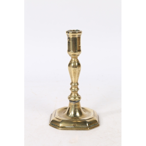 242 - A GEORGE I BRASS CANDLESTICK, CIRCA 1715. with a faceted socket above a faceted and knopped stem rai... 