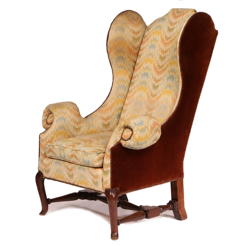 38 - A GEORGE I/II OAK AND UPHOLSTERED WING ARMCHAIR, CIRCA 1730. The padded flat-arched back, downswept ... 