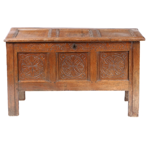 39 - A 17TH CENTURY OAK COFFER. The three panel hinged top above a carved frieze and three flower head ca... 