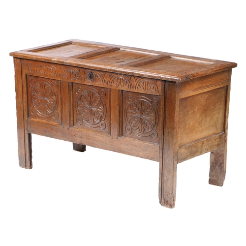 39 - A 17TH CENTURY OAK COFFER. The three panel hinged top above a carved frieze and three flower head ca... 