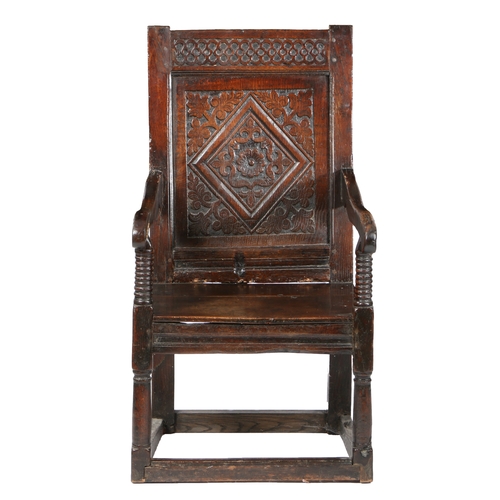 49 - A CHARLES I OAK PANEL-BACK OPEN ARMCHAIR, YORKSHIRE, CIRCA 1640. The back panel carved with a single... 