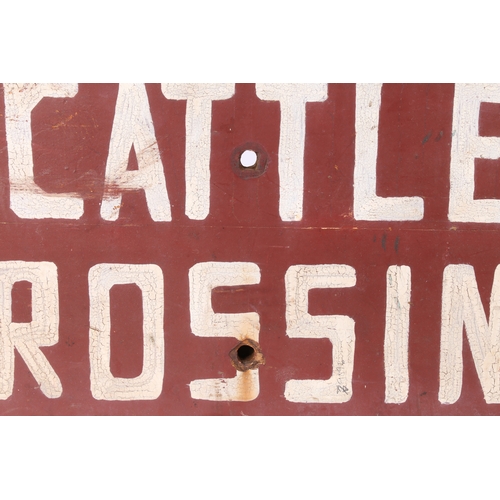 62 - AN AMERICAN FOLK ART SIGN. CATTLE CROSSING, in white lettering and red ground, 64cm wide, 33cm high.