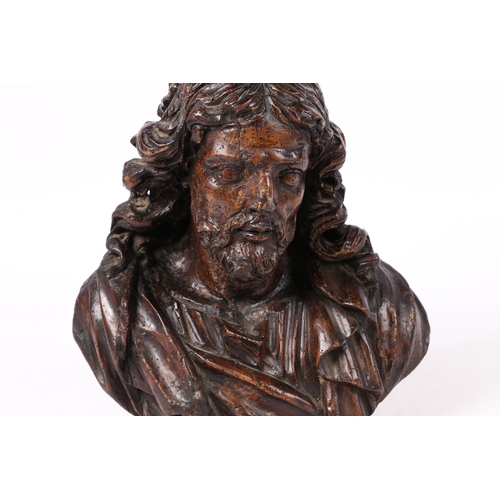 96 - A 17TH CENTURY WALNUT C ARVED BUST OF CHRIST. Flowing curled hair above wearing robes, 37cm high.