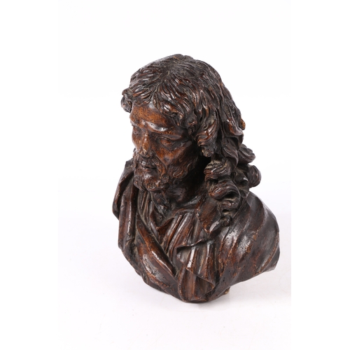 96 - A 17TH CENTURY WALNUT C ARVED BUST OF CHRIST. Flowing curled hair above wearing robes, 37cm high.